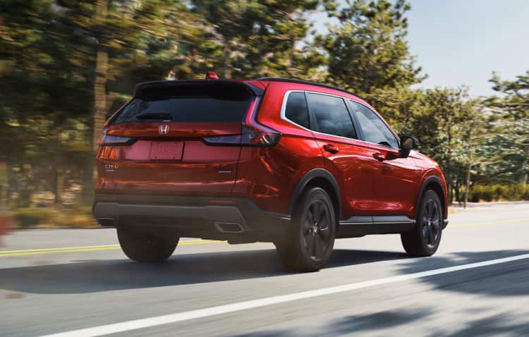 Passenger-side profile view of the 2022 Honda CR-V Touring in Sonic Gray Pearl, driving in an urban environment at night.