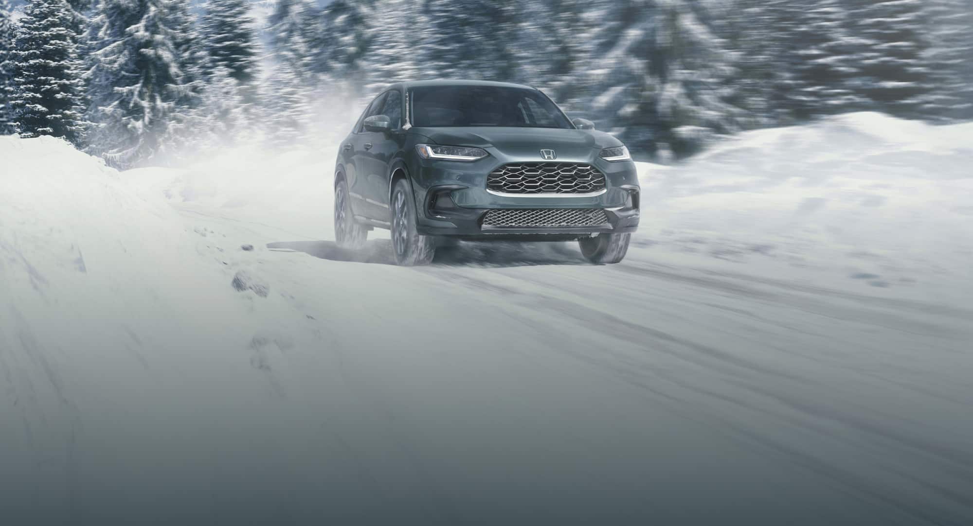 2027 Honda HR-V EX-L in Nordic Forest Pearl front view driving on a snowy road (Subcompact Crossover SUV).